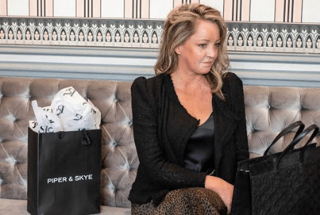 A fashion leader sits on a velvet couch with a shopping bag.